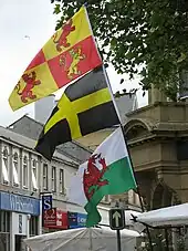 Photo montrant trois drapeaux accrochés à la même hampe dans un décor urbain