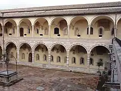 Cloître de Sixte IV avec, sur les deux ordres, les fenêtres romanes de l'ancien édifice (XIIIe&nbsp;siècle) et ce qui reste des fresques du XVIe&nbsp;siècle de Dono Doni et de son fils Lorenzo.