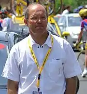 Photo en buste d'un homme partiellement chauve portant des lunettes et une chemisette blanche.
