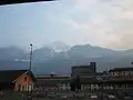 La gare d'Aoste, les bâtiments de l'industrie sidérurgique Cogne et, à l'arrière-plan, le pic de Nona et le mont Émilius.