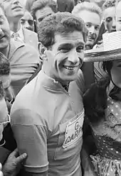 Photographie en noir et blanc d'un cycliste entouré par la foule.
