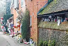 Une maison de briques rouges avec des bouquets de fleurs par terre.