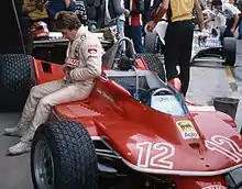 Photo d'un pilote de course assis sur un ponton de sa monoplace de Formule 1