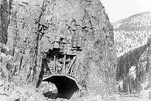Photographie en noir et blanc du tunnel, creusé dans la roche.