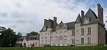 Façade du château, au murs clairs et au toit d'ardoise noire.