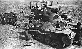 Photo en noir et blanc montrant, au premier plan, un char de combat et, au second plan un camion.