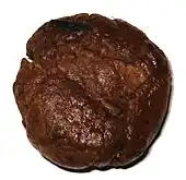 Boule de résine d'aspect cireux et de couleur brun-rouge foncé.