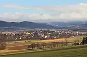 Photographie couleur d'un village dominé par un clocher, au cœur d'une large vallée.
