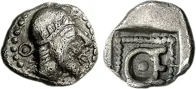 Hémiobole de Thémistocle en Magnésie (vers 465-459 av. J.-C.) où il est montré portant un bonnet serré avec une couronne d'olivier (une coiffe similaire peut être vue sur la monnaie de Kherei&nbsp;(en)). Cela reflète peut-être les bonnets des satrapes achéménides, comme on le voit dans la Tête d'Héraclée du Pont&nbsp;(en). Les initiales « ΘΕ » sont visibles autour du portrait et au revers.