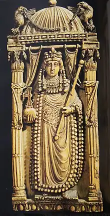 Photographie d'une pièce ouvragée représentant une femme en tenue d'impératrice sous un chapiteau supporté par deux colonnes.