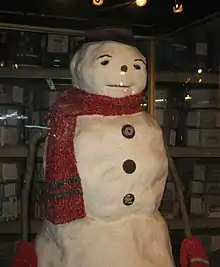 Un bonhomme de neige factice utilisé pendant le tournage du film. Il est fait de 3 boules, porte un bob noir, une écharpe rouge, des bras en bâton avec des moufles et des boutons de manteau sur le torse.