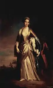 Jeune femme en pied, en robe rouge foncée, au centre d'une toile obscure, quelques arbres se découpant à l'horizon, robe marron satiné très décolletée, étole d'hermine sur l'avant-bras gauche