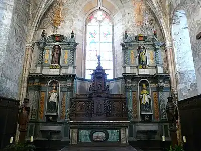 Retable architecturé constitué de deux corps latéraux à double étage et d'un corps central en bois composé du tabernacle, de volets flanqués d'ailerons en volute et couronné d'un dais d'exposition. Jumilhac le grand (24), église Saint-Pierre-ès-Liens.