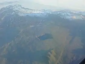 Vue aérienne en direction du sud de l'extrémité occidentale du front glaciaire du Dyngjujökull avec la Kistufell enneigée à droite et le cratère du Urðarháls au premier plan avec à sa gauche le Holuhraun et à sa droite le Dyngjuháls.
