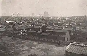 Photo d'un paysage urbain. À perte de vue sont visibles des bâtiments de deux ou trois étages, et quelques cheminées industrielles percent au loin.