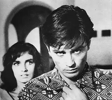 Tom Ripley, ici interprété par Alain Delon dans Plein Soleil (1960), avec en arrière-plan le personnage de Marge, interprétée par Marie Laforêt.