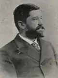 Photographie noir et blanc d'un homme en habit cravate.