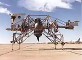 Le deuxième LLRV. À gauche, la cabine en mousse expansée devant simuler le champ de vision réduit du pilote du véritable LEM. À droite, en porte-à-faux, la nacelle contenant l'électronique de bord. Le toit de la cabine en mousse fut retiré à la suite du crash du pilote d'essai Joe Algranti le 8 décembre 1968, car il fut découvert qu'il perturbait les caractéristiques aérodynamiques de l'engin. Au centre, le turbofan CF700-2V sur cardans simulant la pesanteur lunaire.