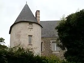 Vue en contre-plongée d'un château de sa tour ronde, en partie masqués par des arbres.