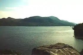 Un lac calme et des collines en arrière-plan.