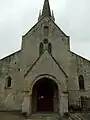 Porche à ouverture plein-cintre, mais dont la voûte est soutenue d'une croisée d'ogives en arc-brisé.