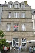 Vue d’une façade de maison en granit, à trois étages.