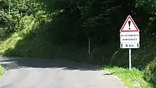Panneau en place sur une route de montagne accompagné d’un panonceau « Accotements dangereux » et d’un panonceau d’étendue de ce danger sur 6&nbsp;km