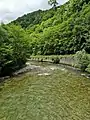 La berge aménagée pour recevoir une voie ferrée est occupée par une route en sens unique vers Saint-Girons.