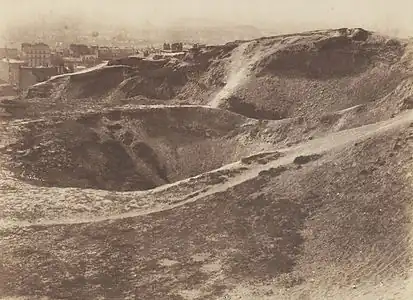 Photographie sépia de carrières destinées à produire du plâtre, avec des monticules de gypse dénudés, arides et sans végétation.
