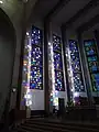 Image prise de l'intérieur de la cathédrale, centrée sur des vitraux colorés.