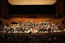 Un orchestre joue sur une scène devant quelques spectateurs.