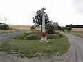 Croix de chemin, à l'arrière-plan : éoliennes.