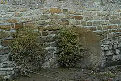 Le menhir de Men Rouz, malheureusement en partie sous les remblais d'un parking et incrusté dans un mur de soutènement