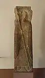 Dans le même bloc, sur la face antérieure de la stèle du XIIe&nbsp;siècle, l'évêque saint Léger ("S.Levdga" dit aussi Leodegar ou Leutgar) qui soutient la construction des bâtiments claustraux. On distingue la tête de l'évêque qui a été martelée au cours de la Révolution.