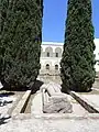 Vue d'une statue allongée avec une épée et un édifice à colonnade à l'arrière-plan.