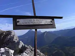 Petit croix métallique avec l'inscription « 11.9.1977 - Au Néron, débonnaire, mais redoutable » et des initiales.