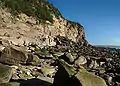 Falaise surplombant plage de galets.