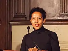 photo couleur en buste de Namwali Serpell derrière un micro