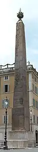 Grande obélisque en pierre sculptée surmontée d'une boule métallique.