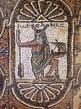 Représentation d'Océan, surmonté de son nom grec Ὠκεανός&nbsp;/ Ōkeanós (écrit ωΚΕΑΝΟϹ), avec ses attributs habituels : pinces de crustacé sur la tête et rame à la main, auxquels ont été rajoutés ici un navire et un dauphin. Église byzantine de Pétra (Jordanie), aile sud, mosaïque (VIe&nbsp;siècle).