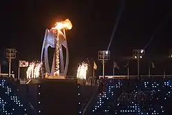 photographie en couleurs d'une vasque illuminée dans un stade la nuit.
