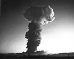 La boule de feu de l'essai thermonucléaire Hood vu du centre de contrôle à 14 km de distance au niveau du sol. L'onde de choc a provoqué le tremblement de fenêtres à 300 miles de distance en Californie, alors que l'éclair lumineux a été aperçu par un pilote d'avion qui volait au-dessus des îles Hawaï, à environ 2 700 miles du Nevada Test Site.