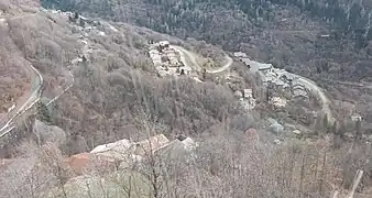 Photographie de plusieurs villages, avec plusieurs maisons installées dans le flanc de la montagne entre la forêt de feuillus sans feuille.