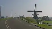 Le moulin (de Vrouw Vennemolen) avec au fond l'église catholique