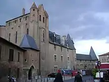 Bâtiment en briques rouges doté de fenêtres à meneaux et toitures pentues en ardoise et lucarnes de toiture.