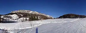 Pentes enneigées traversées par une piste de ski nordique et des montagnes en arrière-plan.