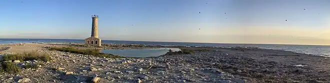 Île dénudée au roc avec un phare en ruine et le lac Érié en arrière plan