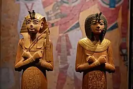 À g. ouchebti au némès doré, tenant le nekhekh. A droite, ouchebti à la perruque ronde. Bois dont ébène, bronze et or