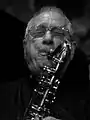 Photo noir et blanc, en gros plan, d'un homme jouant du saxophone.