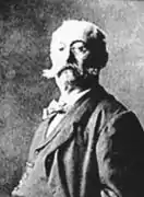 Portrait photographique en couleurs d'un homme en plan taille, tête tournée vers l'ojectif.